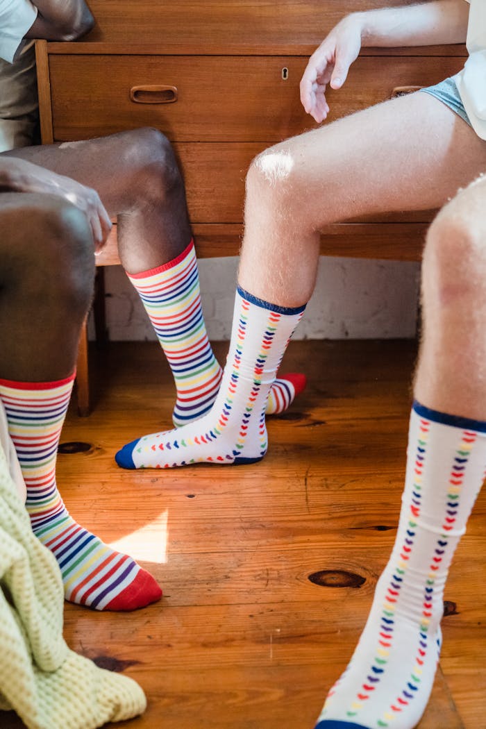 Home Two adults wearing colorful striped socks sitting in a cozy room.